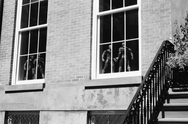 Spiderman figurines inside windows of a brick building